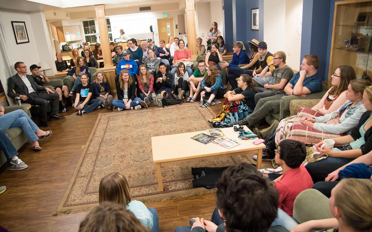 Students sit in a circle in a common area of Scholars LLC while a professor leads a fireside chat