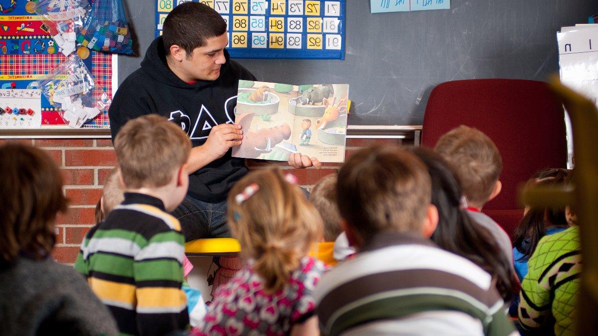 Education student reads a story to a group of young students.