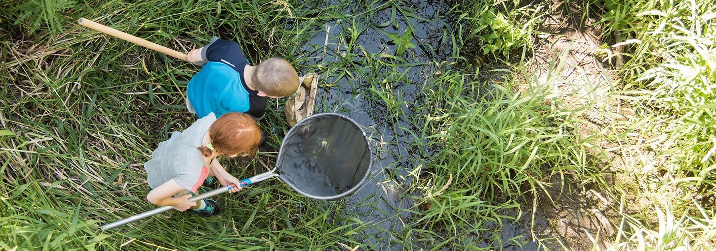 Two children investigate a pond